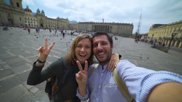 Happy young couple travelling in Colombia taking a selfie photo in the capital Bogota, smiling in the main square Bolivar in Calendaria district