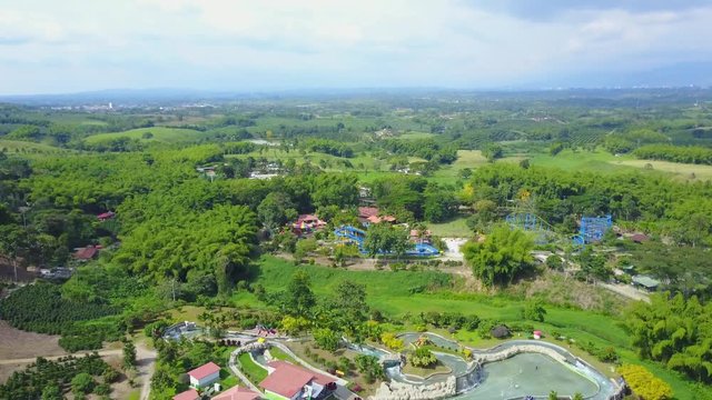 AERIAL: wide push and lift over the Parque del Cafe in Quidio, Colombia, that's been surrounded by coffee plantations.
