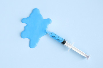 Flat lay of syringe with blue liquid stain abstract.