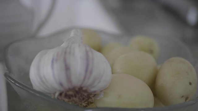 Closeup of potatoes and garlic in a bowl, ready to be cooked.