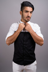 Young handsome Persian businessman against gray background