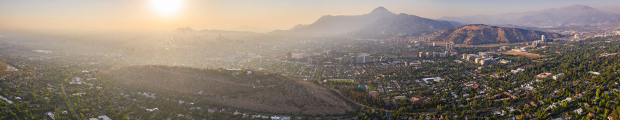 Amazing aerial views of Santiago de Chile city during the sunset with the Andes mountain range making a wonderful horizon line. Urban planning of Santiago from above, streets, trees, houses and parks