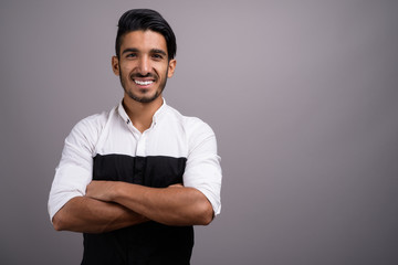 Young handsome Persian businessman against gray background