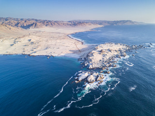 Las Tortolas beach aerial view at Atacama Desert, the sunset ray lights illuminate this amazing and idyllic beach in the middle of the desert on an arid landscape crashed by the Pacific Ocean waters