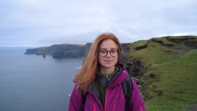portrait of young redhead woman in beautiful rocky landscape. Female on Cliffs of Moher, Ireland