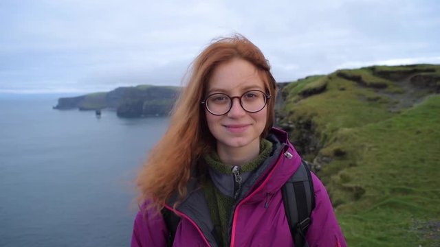portrait of young redhead woman in beautiful rocky landscape. Female on Cliffs of Moher, Ireland