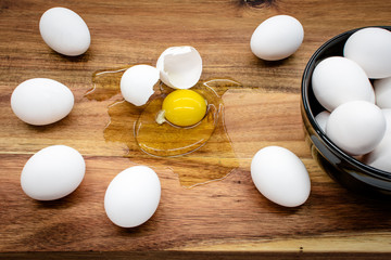 Black bowl with white eggs standing on the wooden table