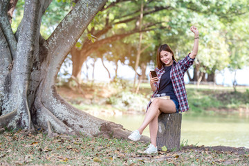 Beautiful woman watching phone, happy in the park