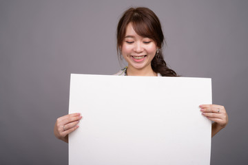 Asian woman holding empty white board with copyspace