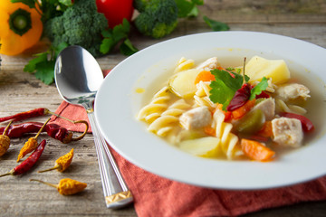 Chicken soup with noodles and vegetables, rustic wooden background. Healthy homemade food.