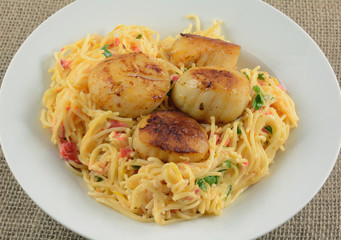 Grilled spicy sea scallops on cheesy pasta in white bowl