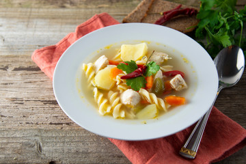 Chicken soup with noodles and vegetables, rustic wooden background. Healthy homemade food.