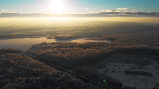 Beautiful sunrise over the snow covered winter landscape. View from the drone of a road in the countryside with cars driving.
