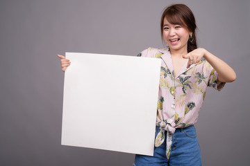 Fototapeta na wymiar Asian woman holding empty white board with copyspace