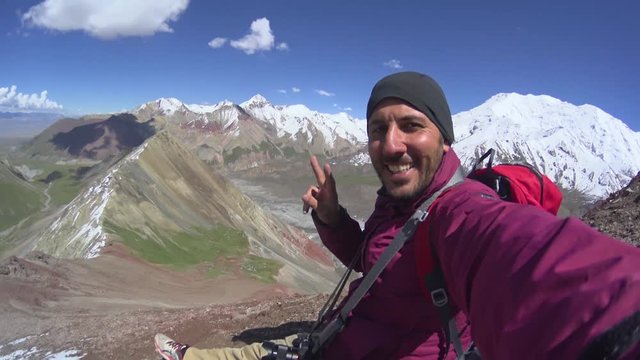 Man climber making a selfie on the top of the mountain near the Lenin peak mountain in Kyrgyzstan, Central Asia