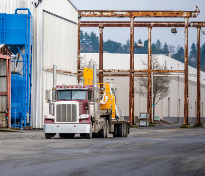 Big rig classic semi truck with step deck semi trailer transporting equipment to warehouse