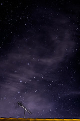 Night sky with stars and clouds over a roof