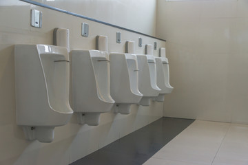 Row of white ceramic urinal chamber pot interior design men public toilet or restroom