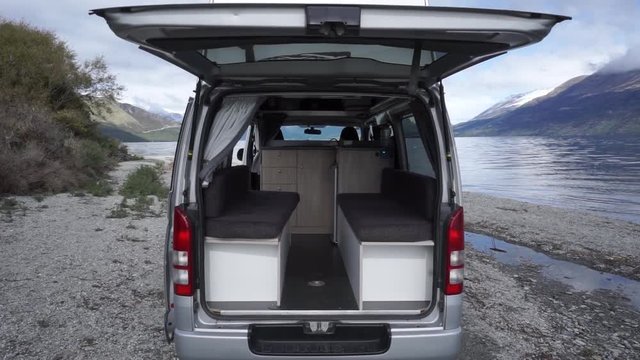 SLOWMO - Exterior and interior of motorhome by beautiful blue Lake Wakatipu, Queenstown, New Zealand with mountains fresh snow cloudy sky in background