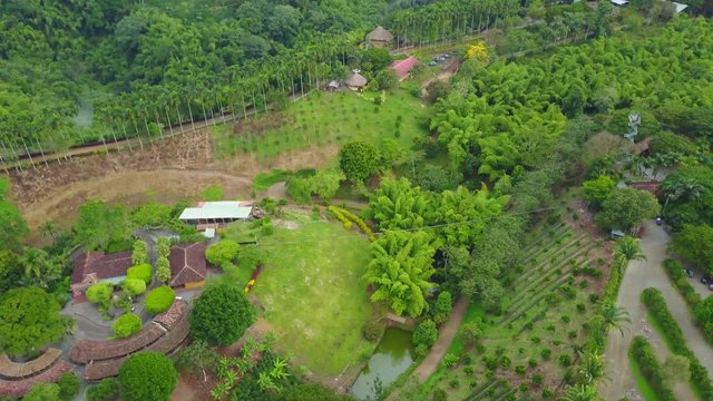 AERIAL: tilting down rotating around the center of the precious Panaca park in Quidio, Colombia, that's been surrounded by coffee plantations.