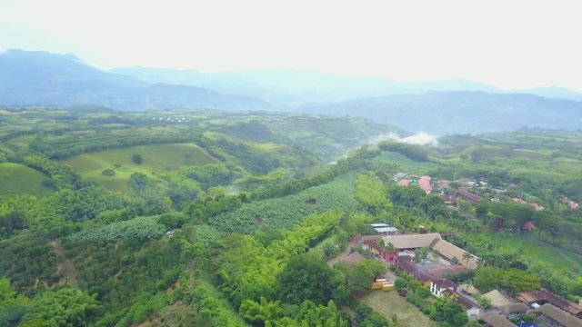 AERIAL: high push towards a smoking area in the forested mountains, over the precious Panaca park in Quidio, Colombia, that's been surrounded by coffee plantations.