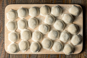 Uzbek national food Chuchvara, like dumplings, on a wooden board, in flour