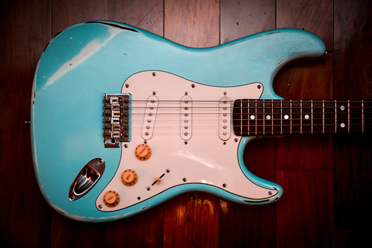 Light blue electric guitar in a brown wood background