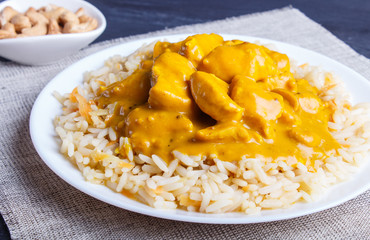 Rice with chicken curry sauce with cashew on black wooden background.