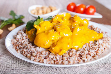 Buckwheat with chicken curry sauce with cashew on brown wooden background.