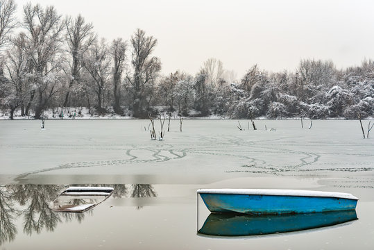 Danube island (&Scaron;odro&scaron;) near Novi Sad, Serbia. Colorful landscape with snowy trees, beautiful frozen river. A boats covered with snow or submerged.
