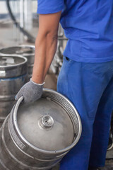 Man putting beer kegs on the production line in the factory