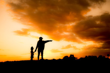 Fototapeta na wymiar Silhouette mother and daughter on the mound at the sky sunset.