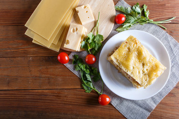 Lasagna with minced meat and cheese on brown wooden background.