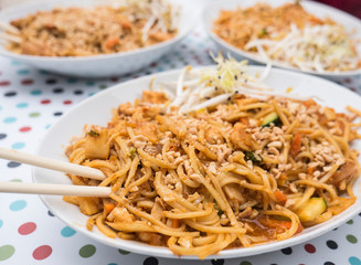 Asian rice noodles with chicken and vegetables close-up on the table. Thai food noodles style and street food on the table.