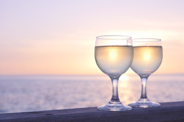 Romantic luxury evening on cruise yacht with winery setting. Glasses, white wine and tropical sunset with sea background. Vacation relax time on the sea of Maldives island.
