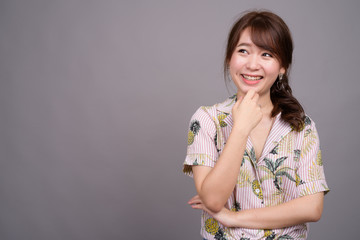 Portrait of young happy Asian tourist woman smiling and thinking