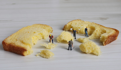 Miniature workers cutting bread. A concept about reducing carbohydrate intake.