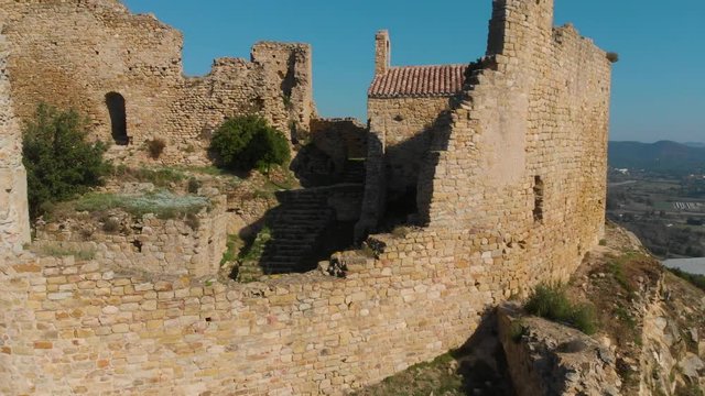 The ruins of the Palafolls Castle and the side of a church on a beautiful sunny day. Catalonia Spain. Aerial view travelling