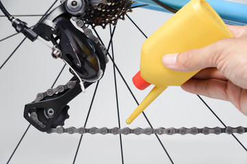 Mechanic oiling bicycle chain and gear with oil