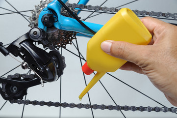 Mechanic oiling bicycle chain and gear with oil