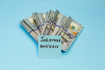 Online or internet business and many US dollar banknotes on blue background. Profits from the sale of online.