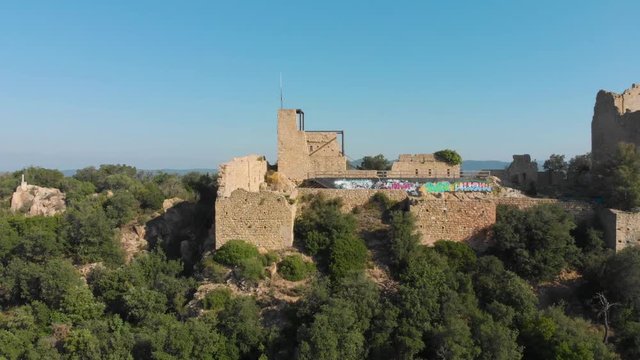 Detail of the ruins of Palafolls Castle on top of the hill on a beautiful sunny day. Catalonia Spain. Aerial view travelling backwards