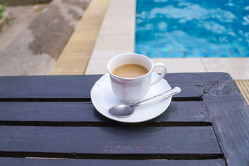 instant coffee on wooden table near swimming pool