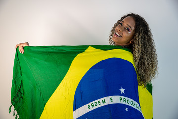 Happy black woman fan holding a Brazilian flag. Brazil colors in background, green, blue and yellow. Elections, soccer or politics.