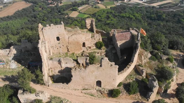 Beautiful landscape of the Palafolls Castle ruins on the top of the hill on a sunny day. Catalonia Spain. Aerial view travelling orbit