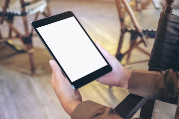 Mockup image of a woman holding black tablet pc with blank white screen while sitting in cafe