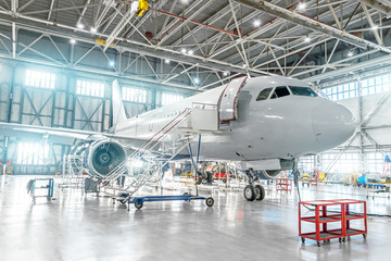 Obraz premium Statki powietrzne w trakcie konserwacji, sprawdzanie systemów mechanicznych w operacjach lotniczych. Samolot w hangarze
