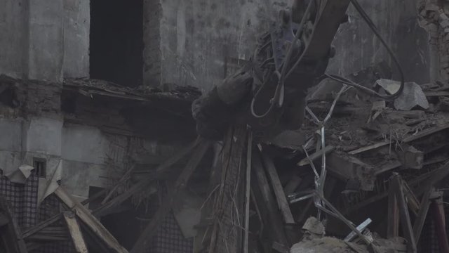 Tearing down and demolishing a beautiful burnt down building with heavy machinery, bulldozers and cranes. Tracking shot.