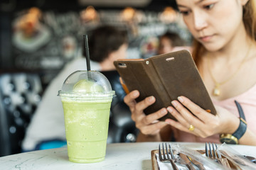 woman holding mobile smart phone taking photo to green tea frappe