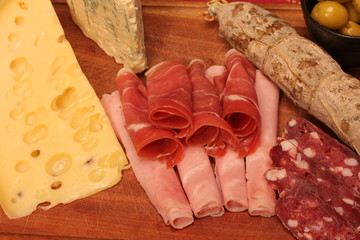 Food tray with delicious salami, pieces of sliced ham and chesses